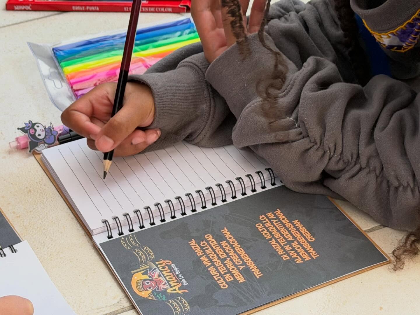 Fotografía de una mano con un lapiz escribiendo en un cuadreno