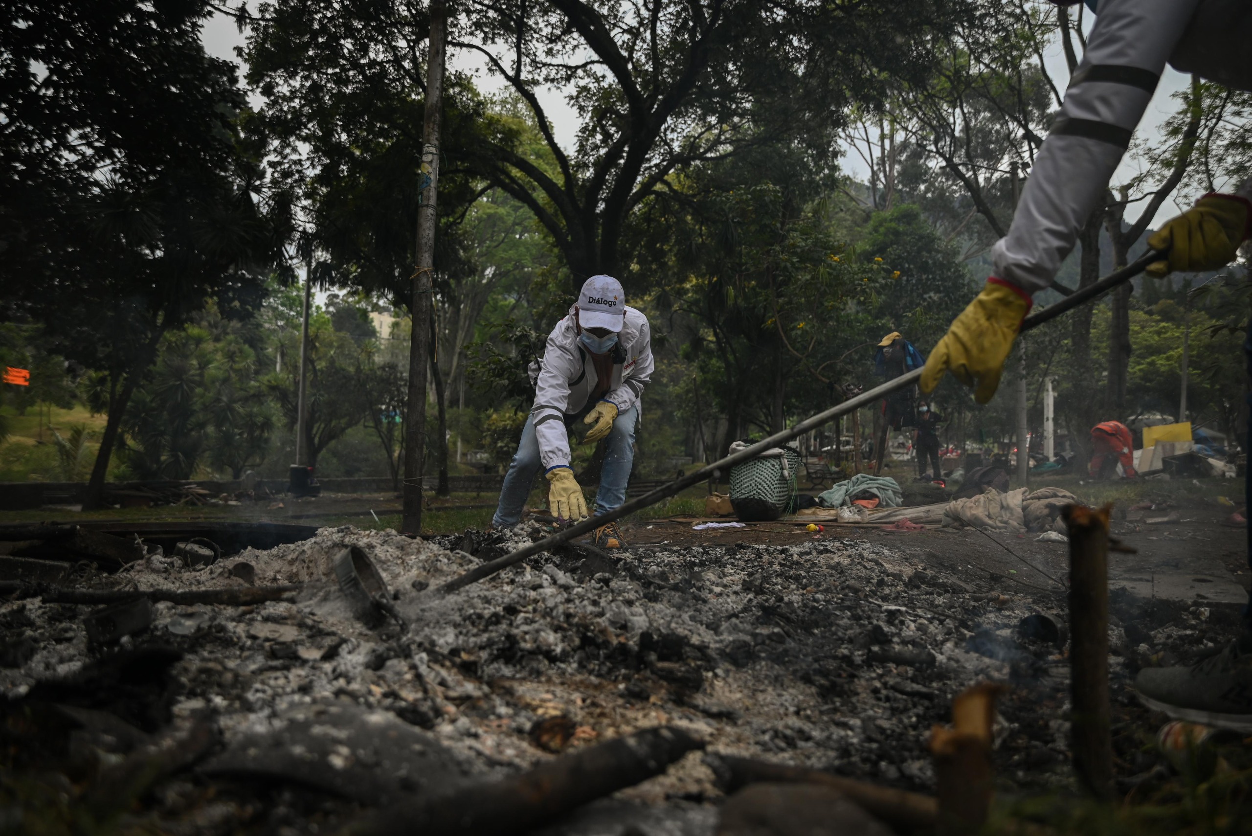 Foto de funcionarios de Diálogo de la SDG, removiendo las brasas con la finalidad de apagar una fogata realizada en el Parque Nacional de Bogotá