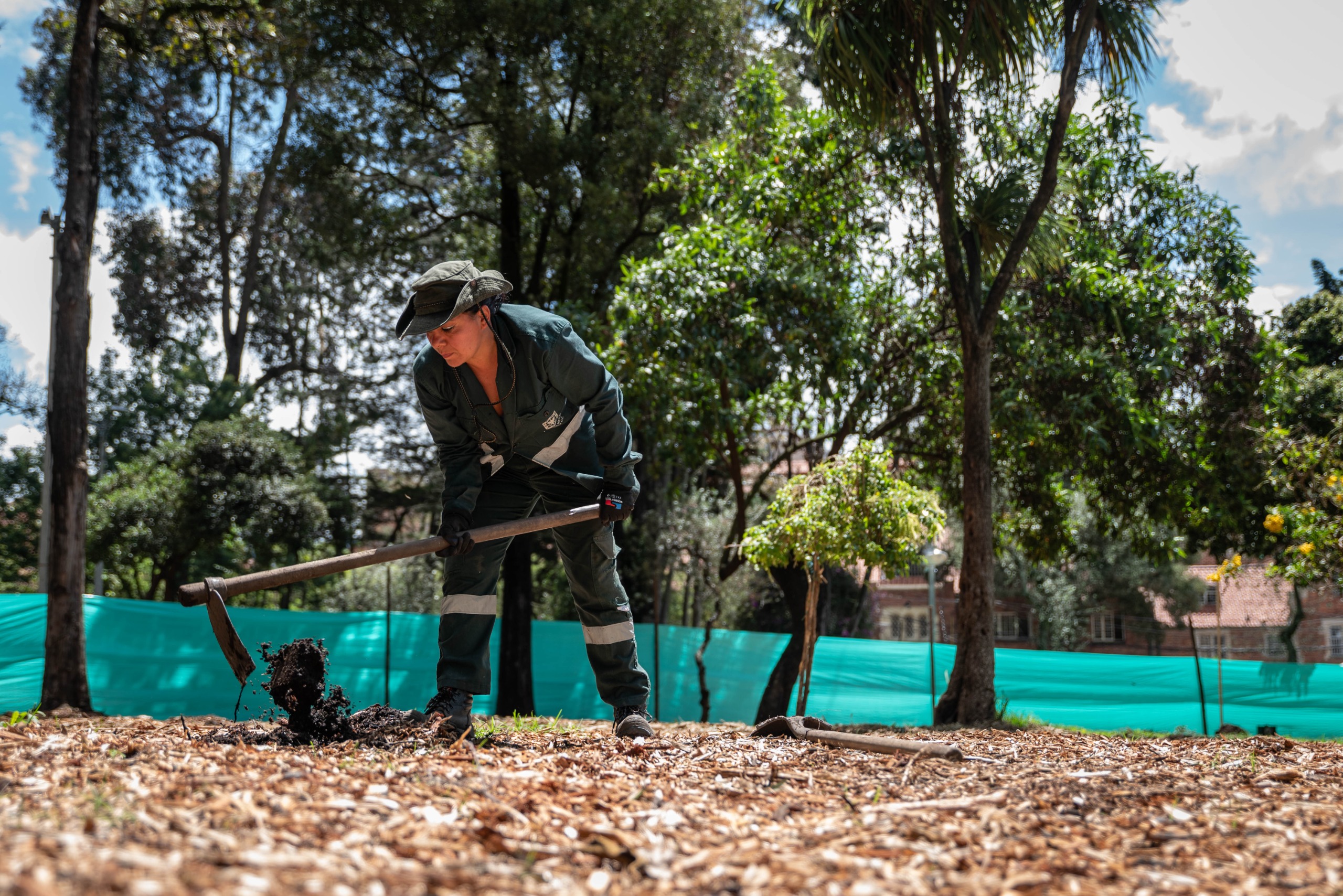 Foto de funcionaria de la Secretaria de Ambiente removiendo la tierra para en el proceso de reforetación del parque