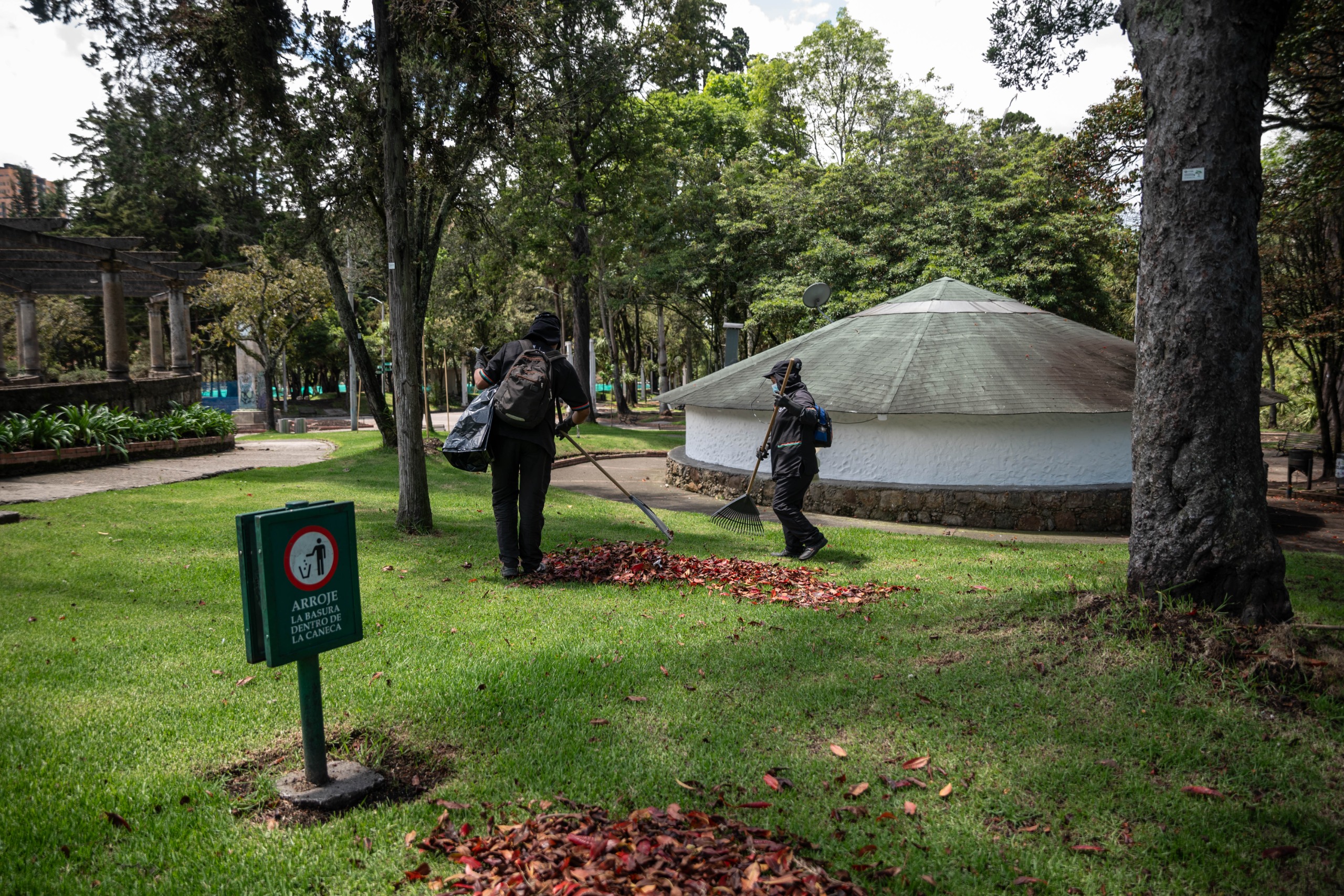 Foto de funcionarios de Aguas de Bogotá barriendo la hojarasca del pasto en el parque
