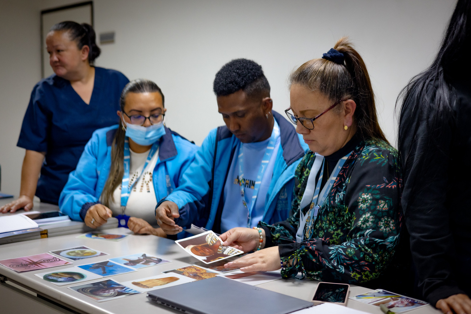 Foto dos mujeres y un hombre de color sentados en una mesa mirando fotografías.
