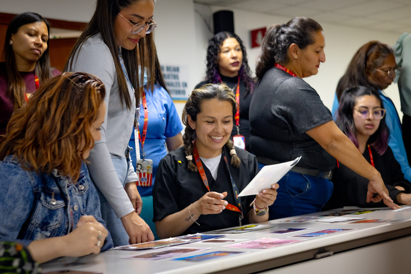 Foto de mujeres sonriendo viendo fotografias en una mesa.