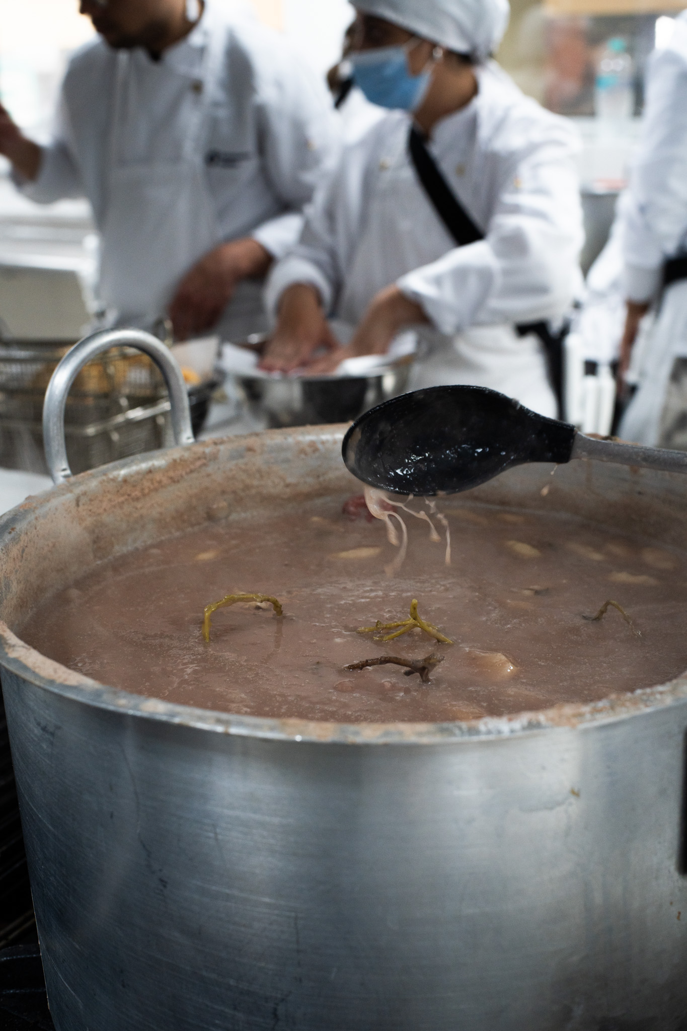 Foto de una olla grande y dos cocineros en acción