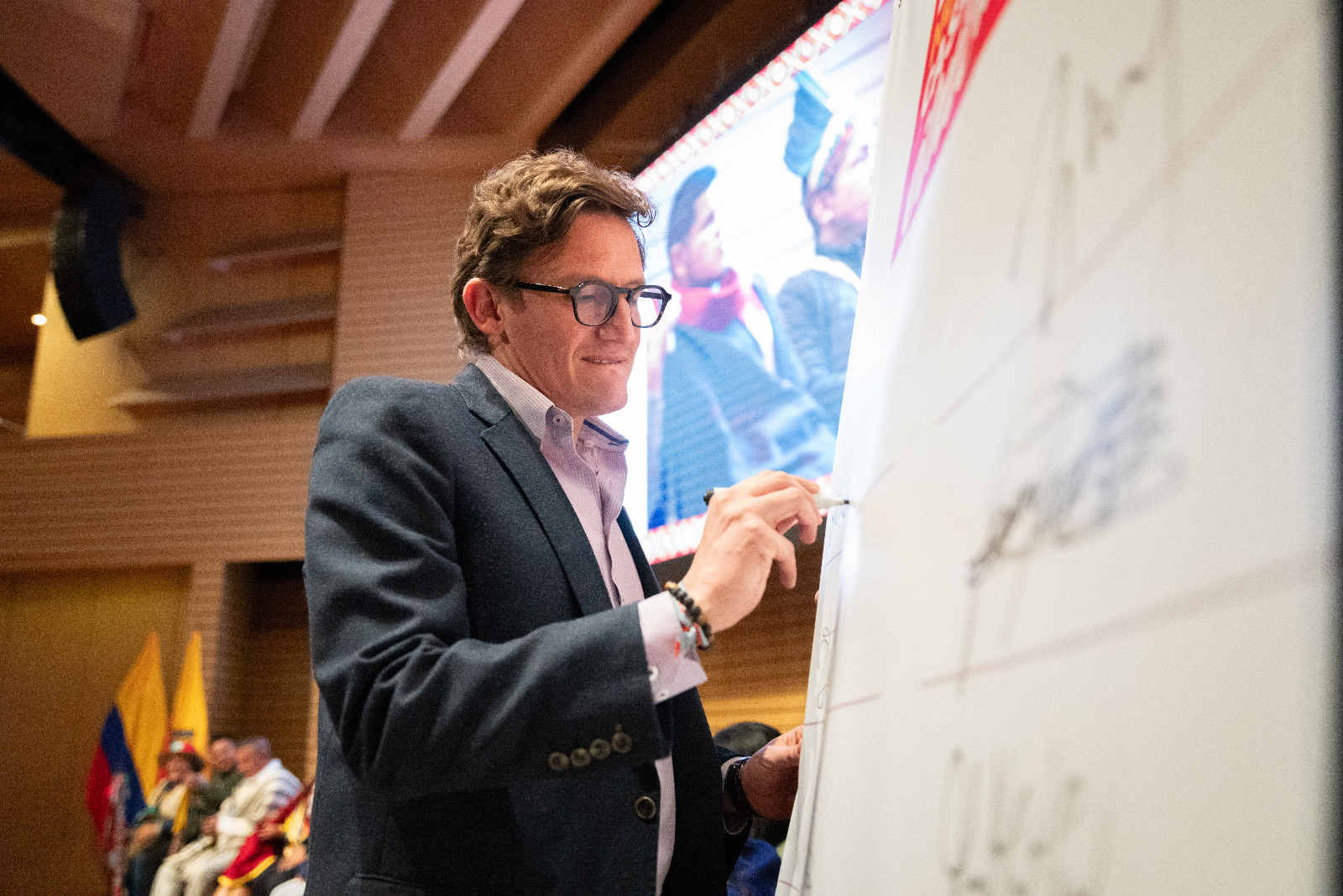 Foto de Gustavo Quintero Ardila escribiendo en un tablero de papel.