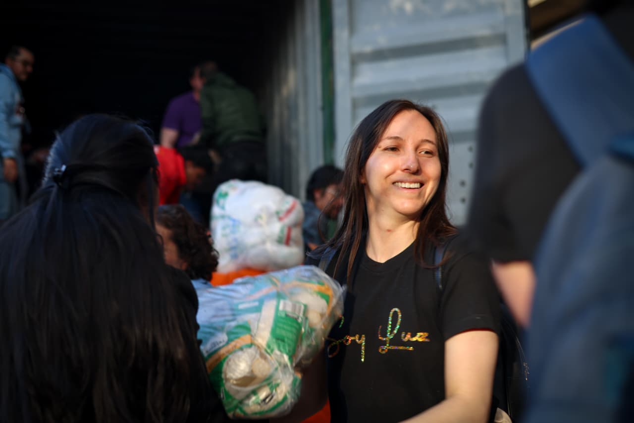 Foto de una cadena humana donde se enfoca en una mujer joven recibiendo donaciones