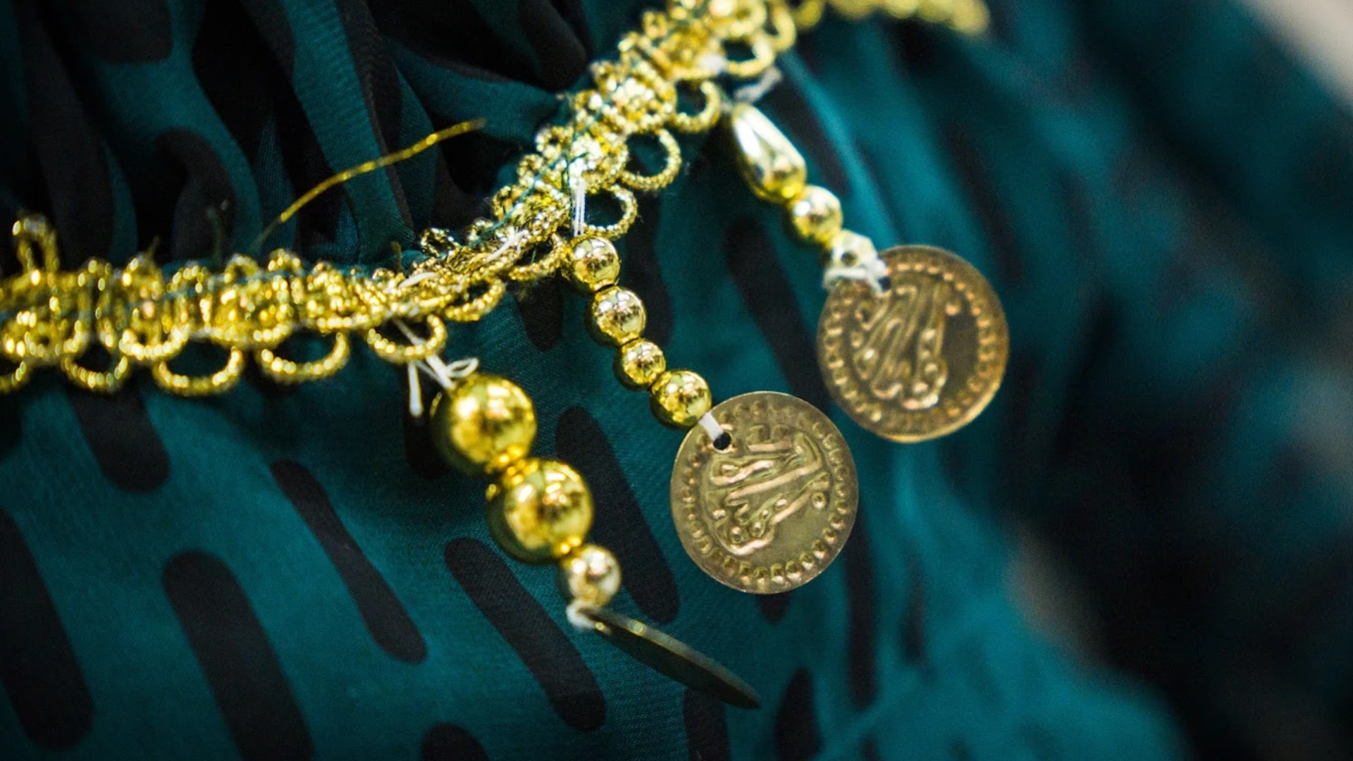 Foto de detalle de un vestido con unos adornos dorados con símbolos del pueblo Rrom
