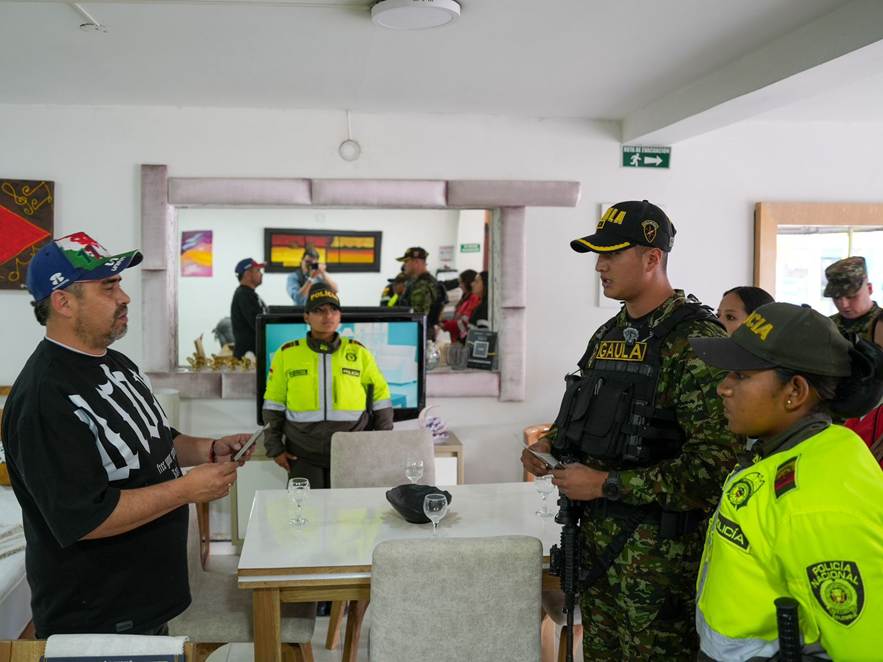 Policías realizan verificación de documentos a un hombre dentro de un establecimiento mientras otros agentes supervisan la situación en el lugar.