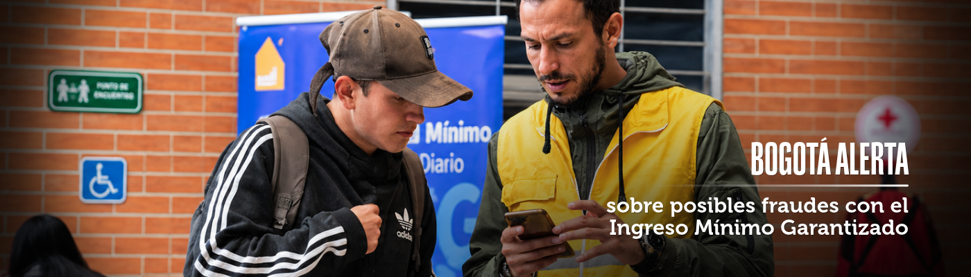 Foto de dos personas interactuando, una con chaleco amarillo y en el diseño un texto que dice "Bogotá alerta sobre posibles fraudes con el Ingreso Mínimo Garantizado"