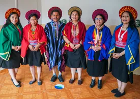 Cinco mujeres y un hombre del pueblo Kamëntsá de pie y sonriendo