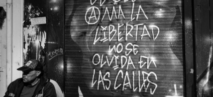 Grafiti en una fachada de local comercial y un señor sentado al lado