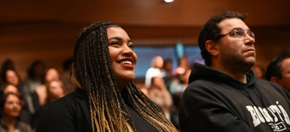 Mujer joven sonriendo, a su lado jóven prestando atención a la charla