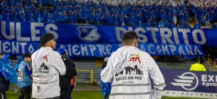 Gestores de diálogo en el estadio y de fondo la barra azul de Millonarios