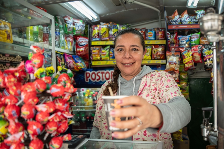 Foto de un joven soriendo ofreciendo un cono de helado.