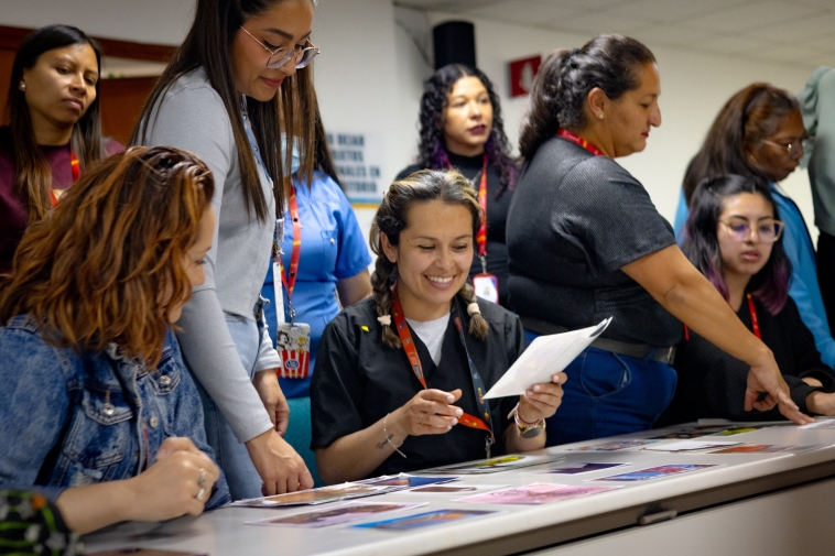 Foto de mujeres sonriendo viendo fotografias en una mesa.