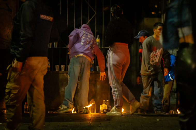 Foto de varias personas en la noche cerca de velas colocadas en la calle