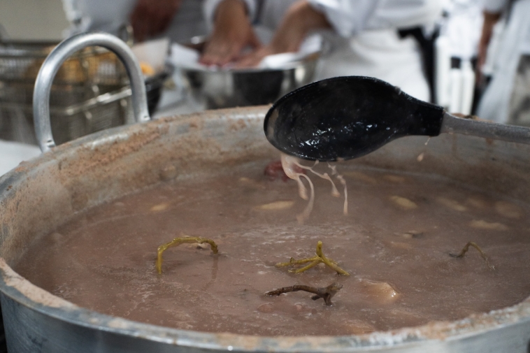Foto de una olla grande y dos cocineros en acción