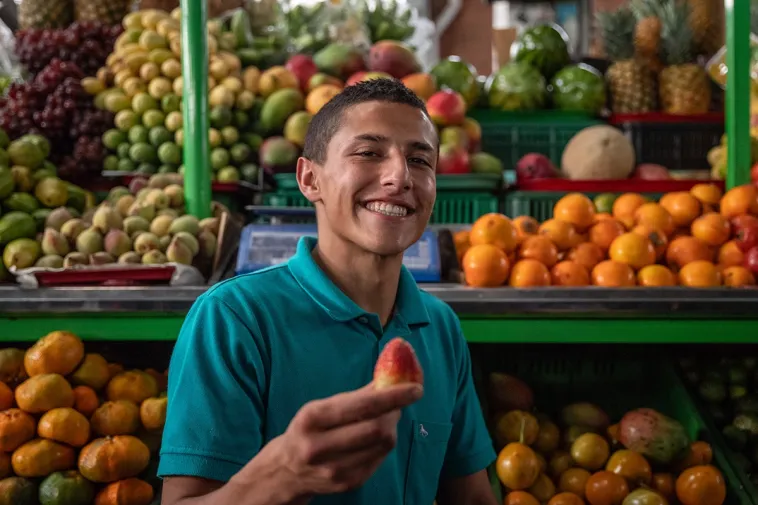 Foto de un joven sonriendo mostrando una fresa fresca