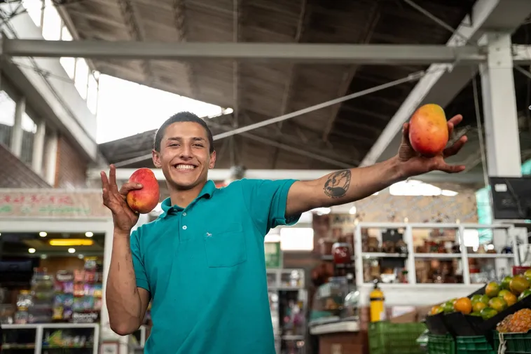 Foto de un joven mostrando dos mangos frescos