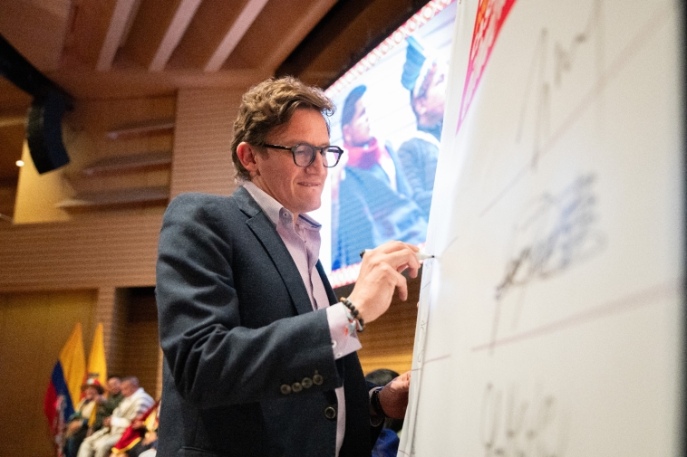 Foto de Gustavo Quintero Ardila escribiendo en un tablero de papel.