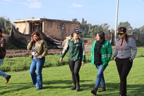 Foto de la alcaldesa local y tres personas más de diferentes entidades caminando en una zona verde ubicada en el humedal Meandro del Say.
