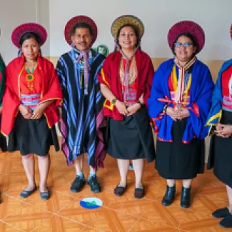 Cinco mujeres y un hombre del pueblo Kamëntsá de pie y sonriendo