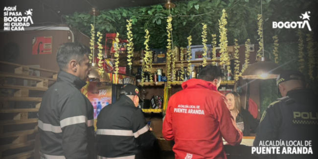 Personal de la Alcaldía Local de Puente Aranda y la Policía Nacional inspeccionan la documentación y el cumplimiento de normas en un establecimiento comercial durante una jornada de seguridad y convivencia en la localidad.