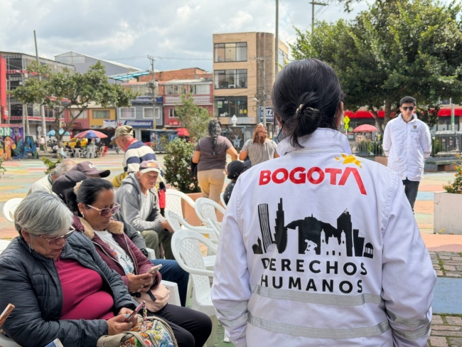 Fotografía de una funcionaria con chaqueta blanca de diálogo en campo