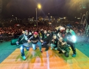 Artistas posan sobre el escenario frente a una multitud durante un festival de hip hop nocturno, en un ambiente lleno de energía, música y cultura urbana.